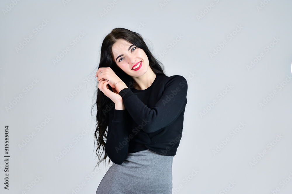 Concept of business female photo portrait with emotions. Portrait of a brunette girl with a smile with long hair with excellent makeup in a gray dress on a white background in different poses. Concept of business female photo portrait with emotions. Portrait of a brunette girl with a smile with long hair with excellent makeup in a gray dress on a white background in different poses.