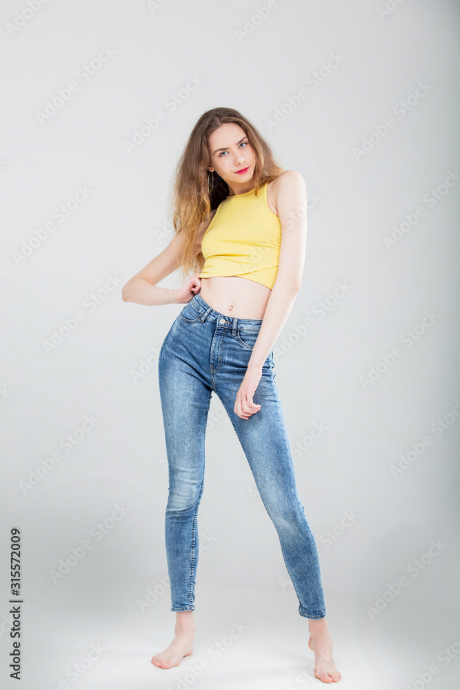 Young beautiful girl model in skinny jeans and top in Studio on white  background Stock Photo | Adobe Stock