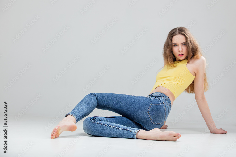 Young beautiful girl model in skinny jeans and top in Studio on white background