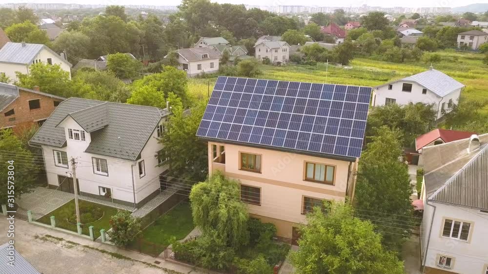 Aerial top view of new modern residential house cottage with blue shiny solar photo voltaic panels system on roof. Aerial top view of new modern residential house cottage with blue shiny solar photo voltaic panels system on roof.