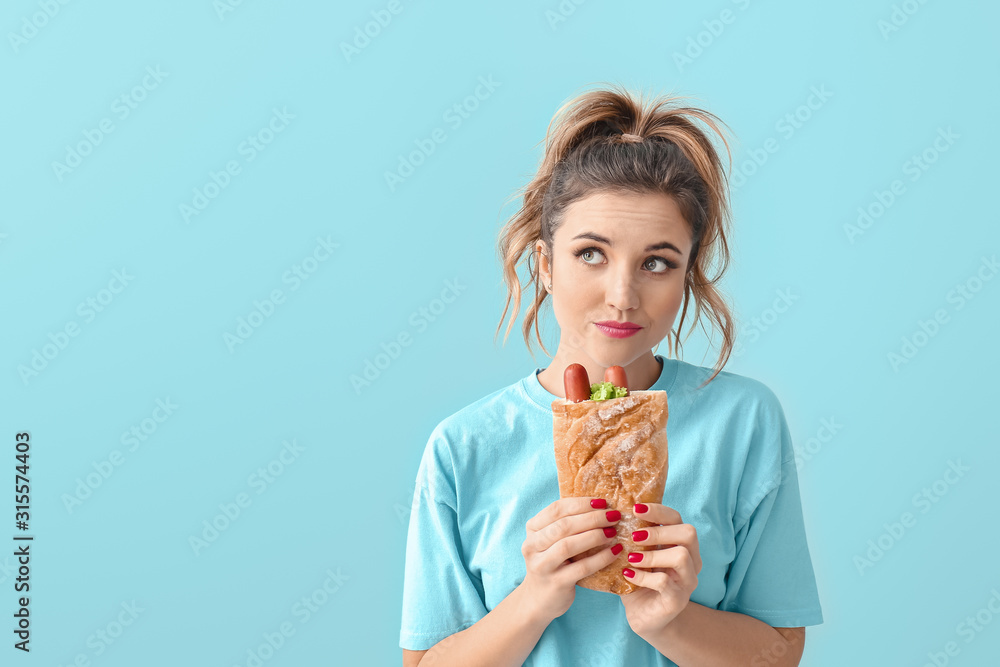 Portrait of thoughtful young woman with French hot dog on color background Portrait of thoughtful young woman with French hot dog on color background