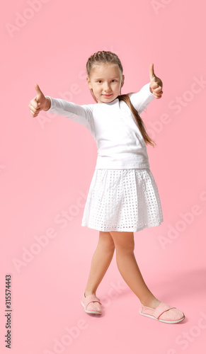 Cute little girl showing thumb-up gesture on color background