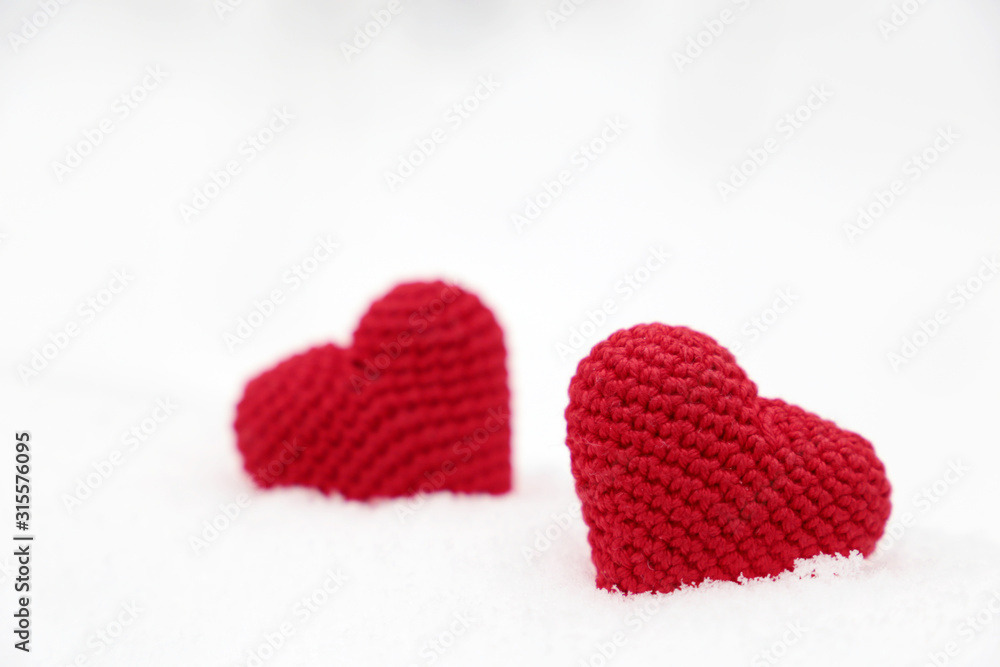 Love hearts, Valentine's card, two red knitted symbols of passion in the snow drift. Background for romantic event, celebration or winter weather Love hearts, Valentine's card, two red knitted symbols of passion in the snow drift. Background for romantic event, celebration or winter weather