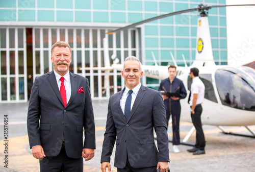 Portrait of Three confident business people standing against his private helicopter at landing airport. Professional career success concept © FotoArtist