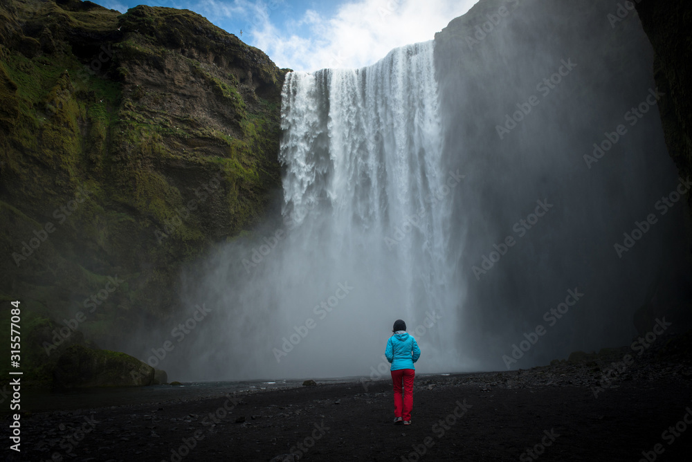 Woman admiring Skogafoss waterfall in Iceland - obrazy, fototapety, plakaty 