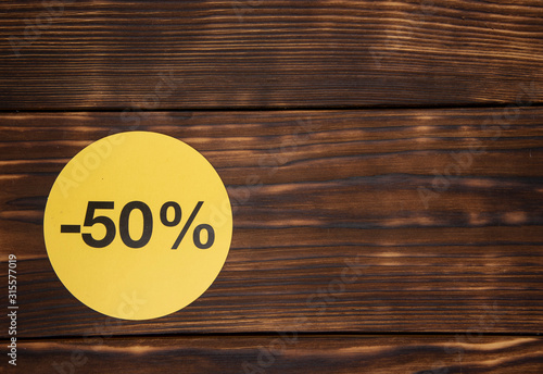 Yellow signs with discount percentages on a wooden background.