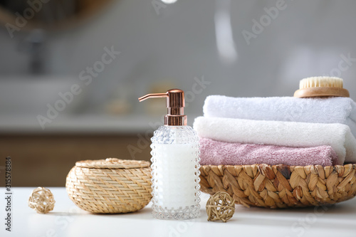 Soap dispenser, towels and brush on white table indoors