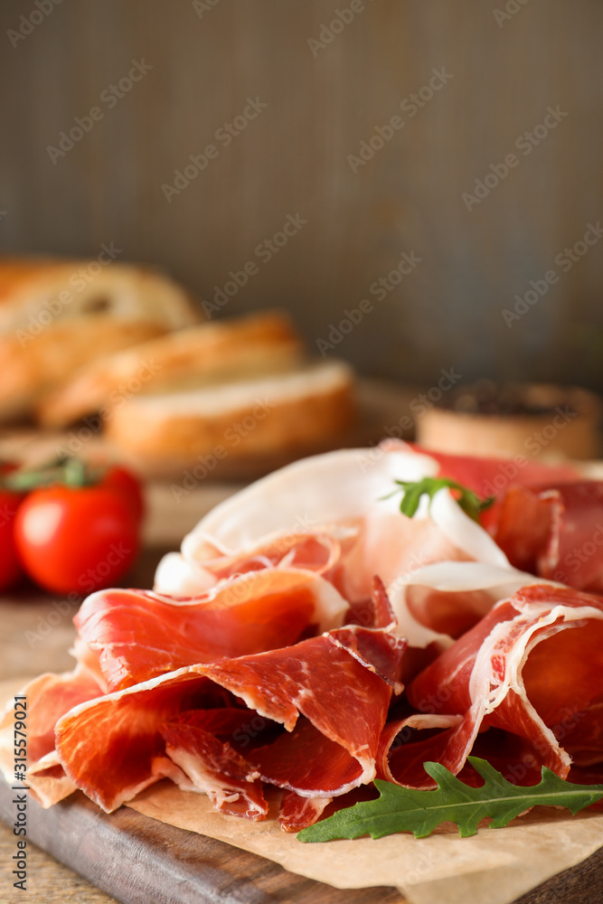 Pile of tasty prosciutto on wooden table
