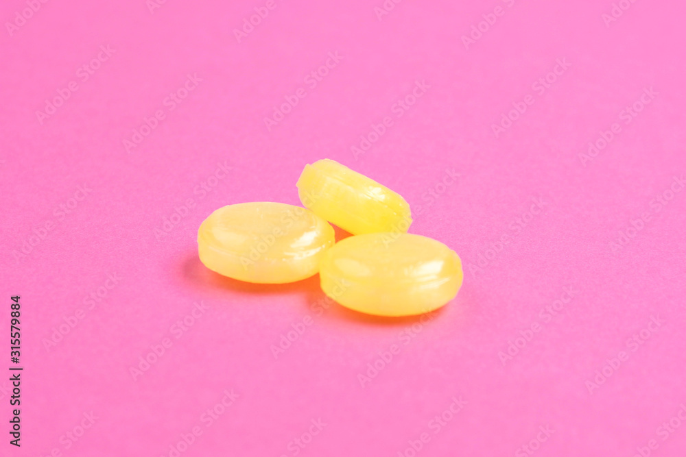Tasty lemon flavored drops on pink background Tasty lemon flavored drops on pink background