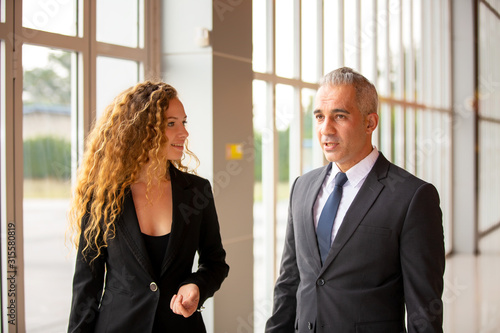 Caucasian businessman and women standing with luggage and talking in airport terminal