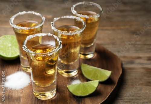 Mexican Tequila shots, lime and salt on wooden table