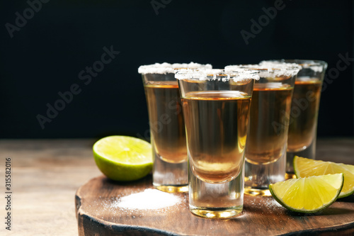 Mexican Tequila shots, lime and salt on wooden table