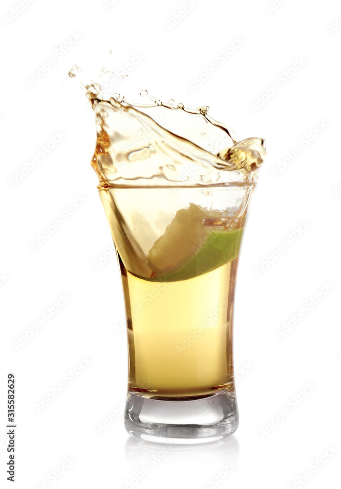 Splashing Mexican Tequila in shot glass with lime slice isolated on white Splashing Mexican Tequila in shot glass with lime slice isolated on white
