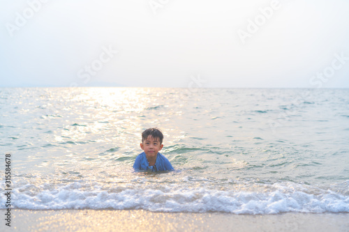 A boy is playing sand and swimming with his brother on the beach.