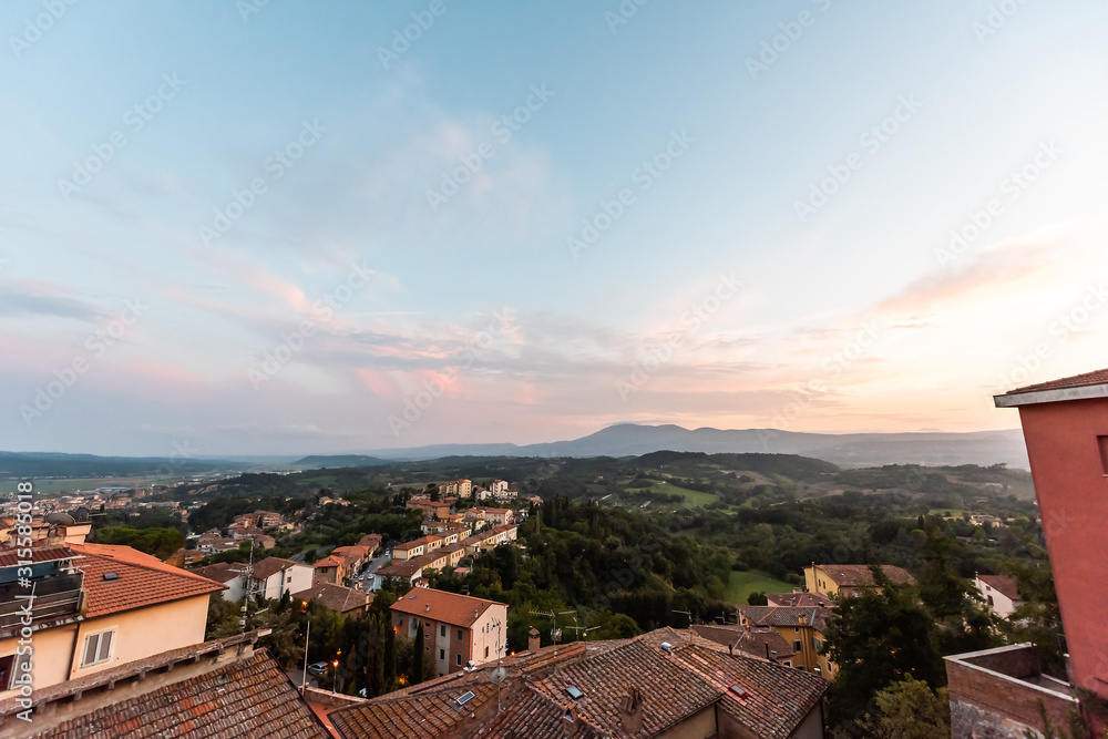 Obraz premium Chiusi, Italy small Tuscany town village at sunset evening with rooftop houses on mountain countryside rolling hills and colorful cityscape with pink clouds