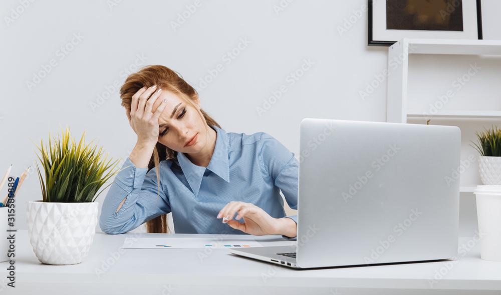 Young office girl sitting at her workplace feeling bad. Woman has a headache Young office girl sitting at her workplace feeling bad. Woman has a headache