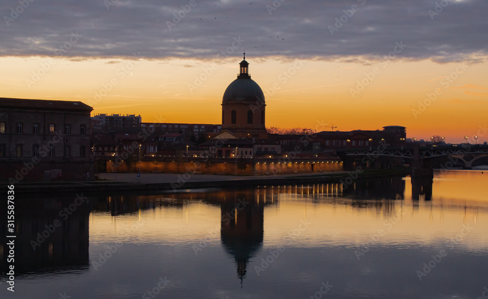 Sunset in the Toulouse with the reflection of the building in the water