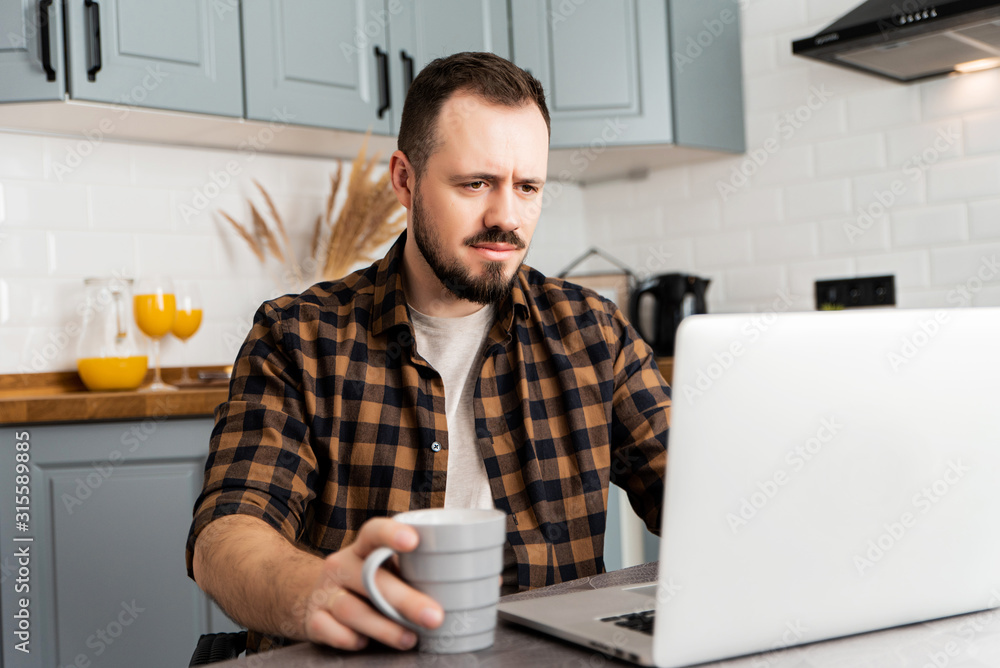 Guy with a cup of coffee is working on a laptop. Guy with a cup of coffee is working on a laptop.