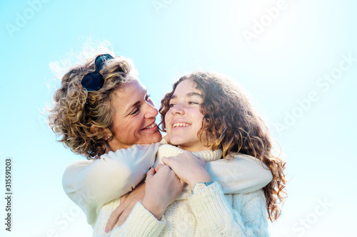 Young woman with her daughter in a very loving attitude. Burnt sky copy space