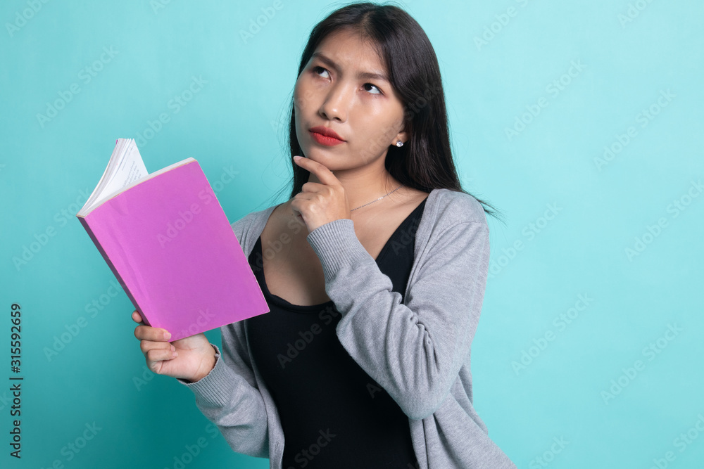 Young Asian woman with a book is thinking. Young Asian woman with a book is thinking.