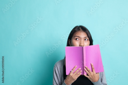 Young Asian woman with a book cover her face.