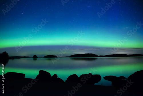 Northern lights dancing over calm lake. Farnebofjarden national park in Sweden. © Conny Sjostrom