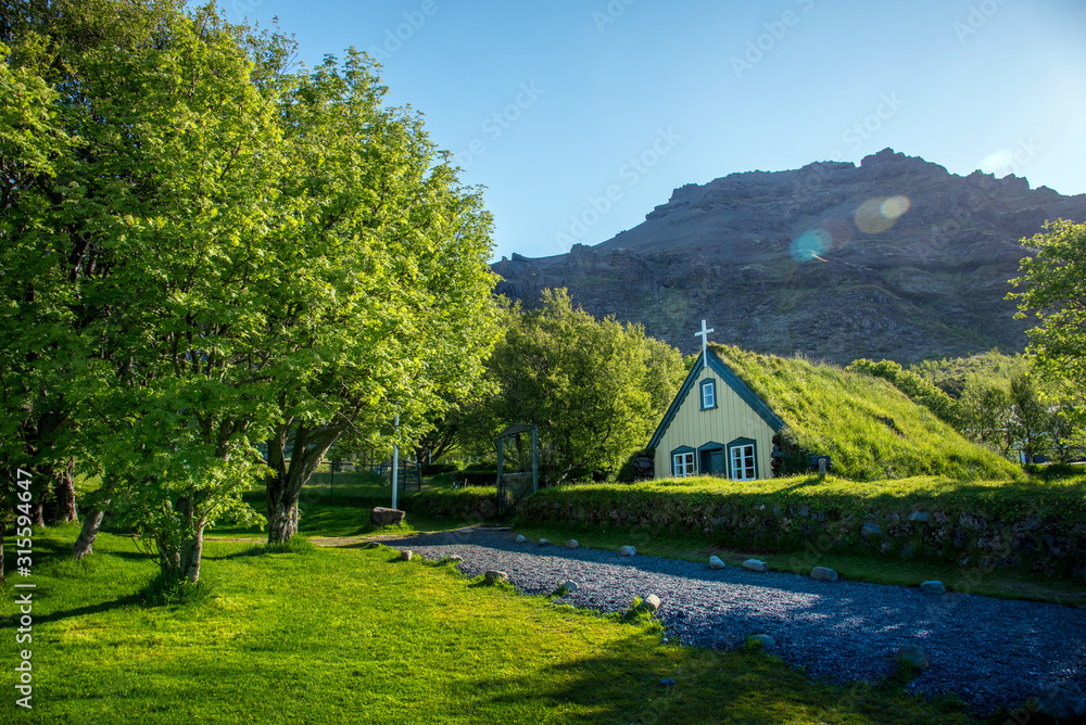Charming mystical scene with turf roof church in old Iceland traditional style and mystical cemetery in Hof, Skaftafell, Vatnajokull National Park. Exotic countries.