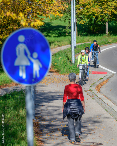 Radfahrer fahren vom Radweg auf einen kombinierten Rad- und Gehweg mit Fußgängern photo