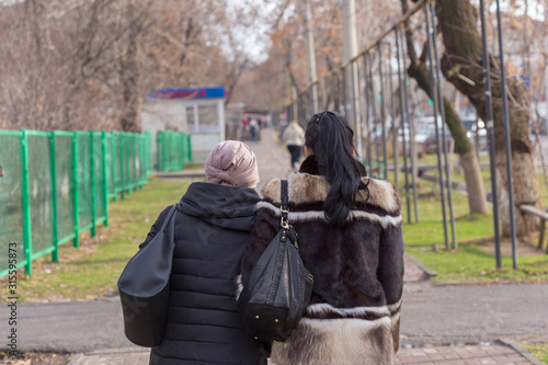 two girls walk on the sidewalk in late autumn or winter