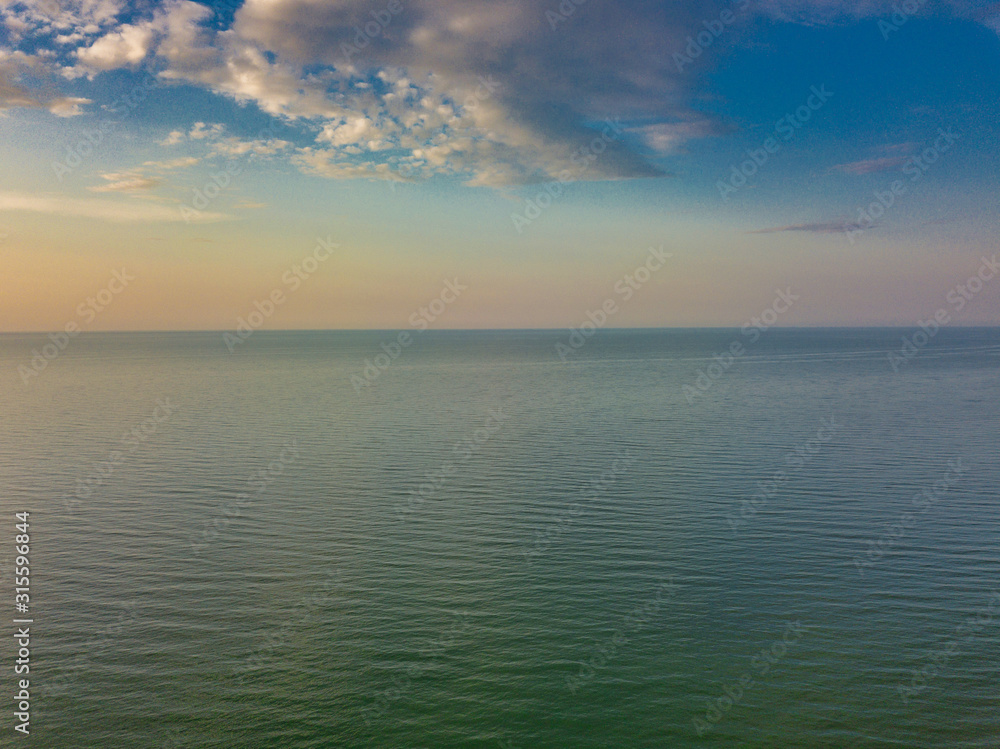 Aerial panoramic view of sunrise over sea. Nothing but sky, clouds and water. Beautiful serene scene