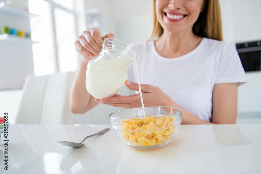 Cropped photo of housewife hands holding pouring fresh milk cooking breakfast cornflakes tasty healthy eating concept white light kitchen indoors Cropped photo of housewife hands holding pouring fresh milk cooking breakfast cornflakes tasty healthy eating concept white light kitchen indoors