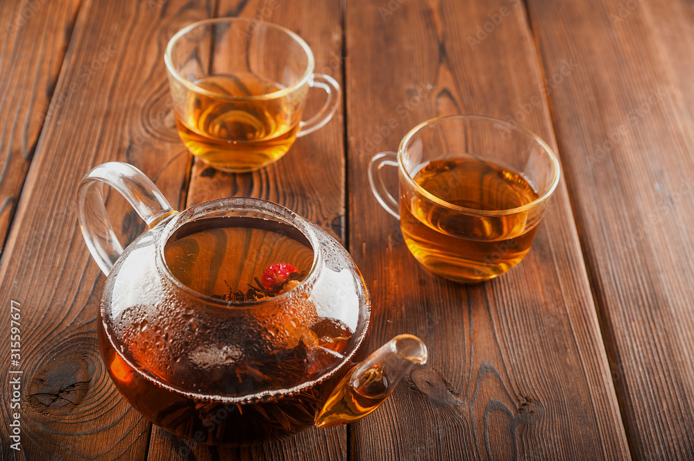Knitted blooming tea in a transparent teapot close-up. Tea ceremony on a dark wooden background and copy space. Knitted blooming tea in a transparent teapot close-up. Tea ceremony on a dark wooden background and copy space.