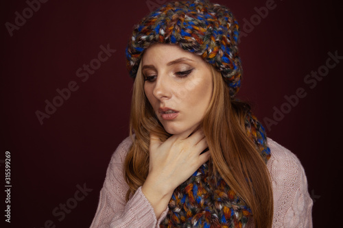 Sore throat concept. Sick woman in hat and scarf holding her nech and felling bad photo