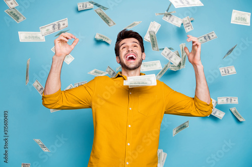 Photo of screaming excited emotional guy having won jackpot in lottery smiling toothily isolated over blue pastel color background in yellow shirt photo