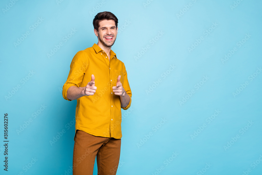 Photo of laughing fooling guy teasing you with jokes pointing at you wearing yellow shirt pants trousers isolated over pastel blue color background Photo of laughing fooling guy teasing you with jokes pointing at you wearing yellow shirt pants trousers isolated over pastel blue color background