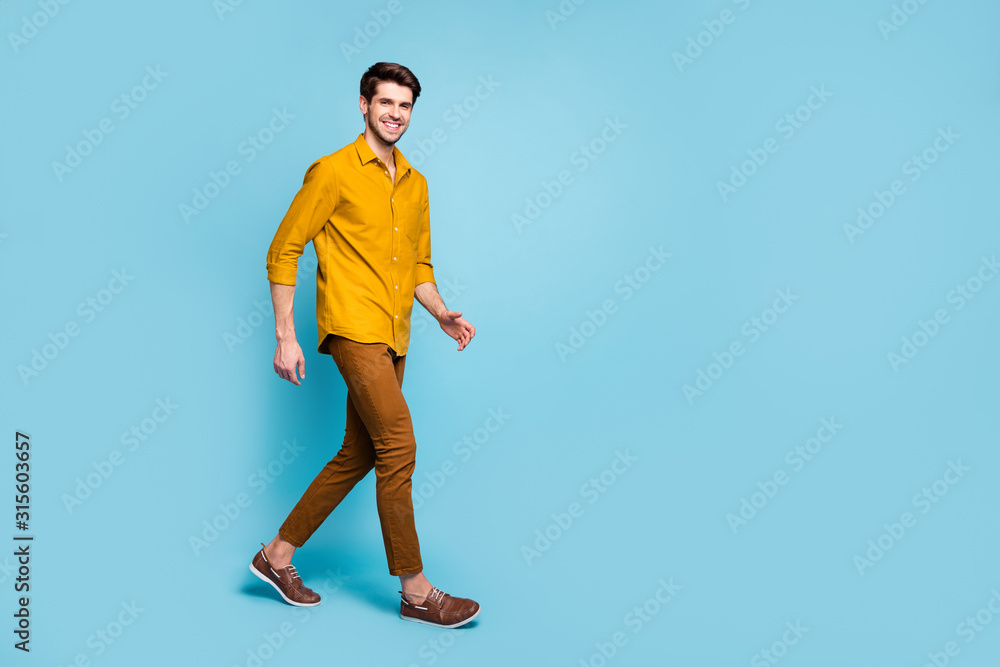Full length body size turned photo of cheerful nice attractive man smiling toothily expressing emotions with face going isolated over blue pastel color background