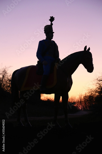 Tableau sur toile Unknown equestrian hussar posing on horseback at sunset on hilltop