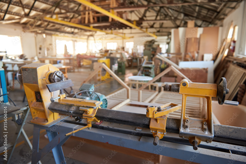 Industrial lathe sitting inside of a large carpentry workshop