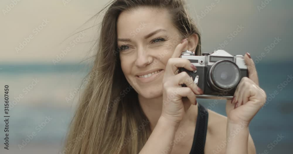cute female photographer using her analogue camera at the beach. Sea in the background. Slow motion 4K cute female photographer using her analogue camera at the beach. Sea in the background. Slow motion 4K