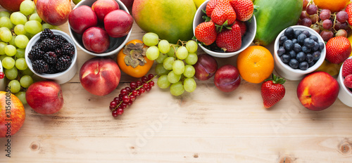 Fototapeta Naklejka Na Ścianę i Meble -  Healthy colorful fruits berries, strawberries oranges plums grapes mango papaya red currants peaches on wooden table, top view, copy space, selective focus