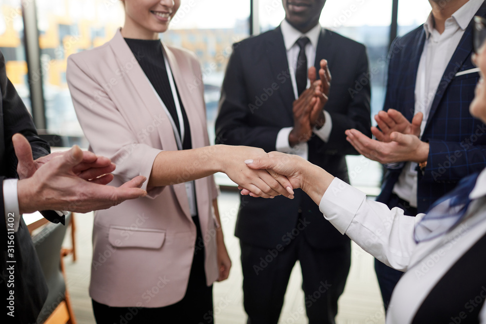 Group of business people standing and clapping they shaking hand to their colleague and congratulating him