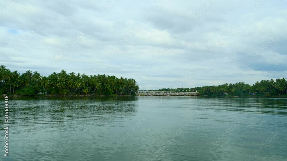 Serene view of beautiful trees and a bridge in the morning, while travelling by boat in a town in Kerala. Serene view of beautiful trees and a bridge in the morning, while travelling by boat in a town in Kerala.