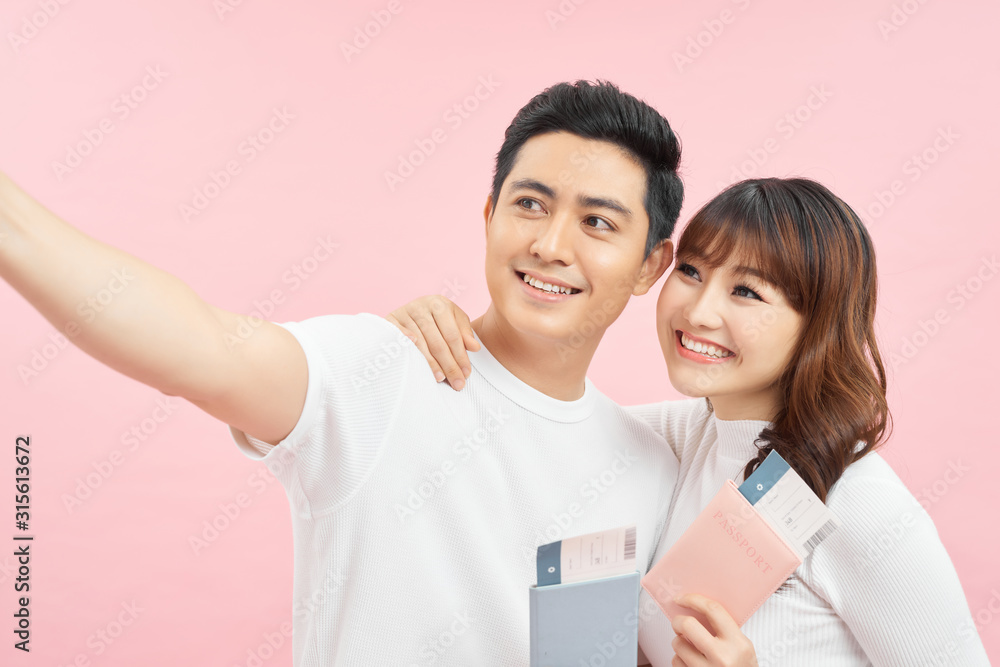 happy asian man and woman holding passports and air tickets while looking at camera isolated on pink happy asian man and woman holding passports and air tickets while looking at camera isolated on pink