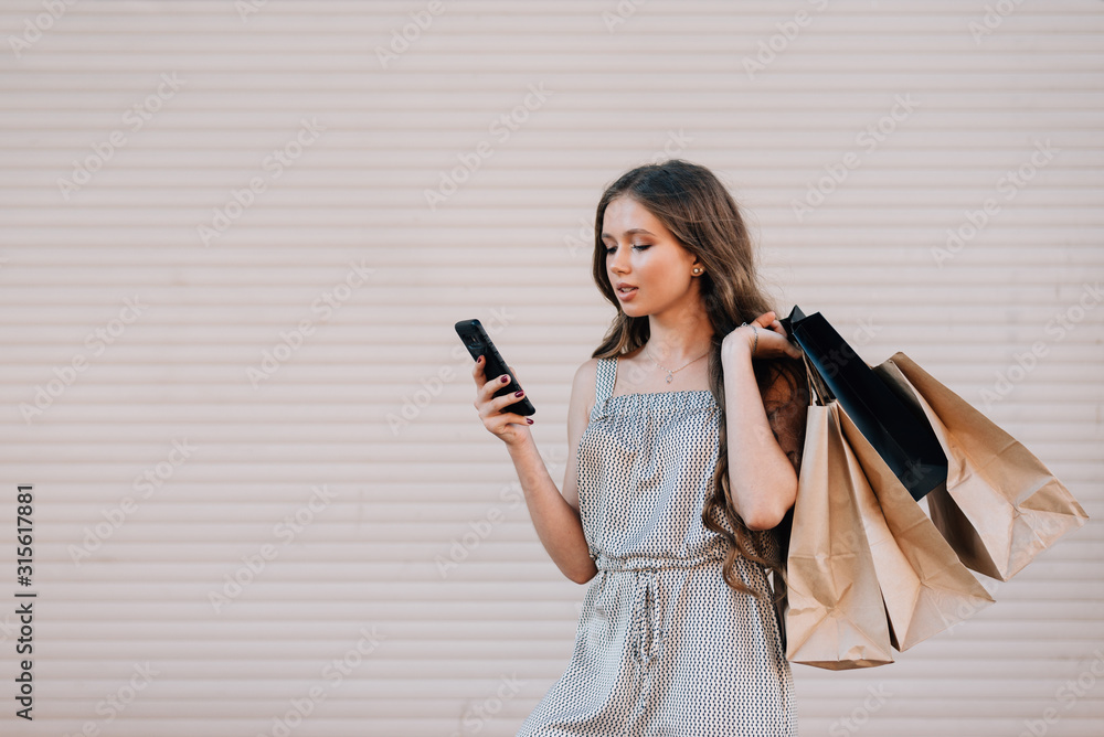 A girl with long blond hair holds shopping bags and looks into the phone, close-up A girl with long blond hair holds shopping bags and looks into the phone, close-up