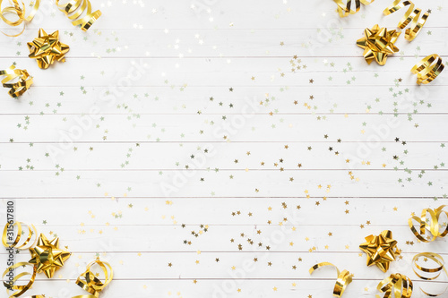Gold confetti stars and ribbons on a White background. Copy space Flat lay. Greeting card for birthday party, Christmas Wedding mother's Day.
