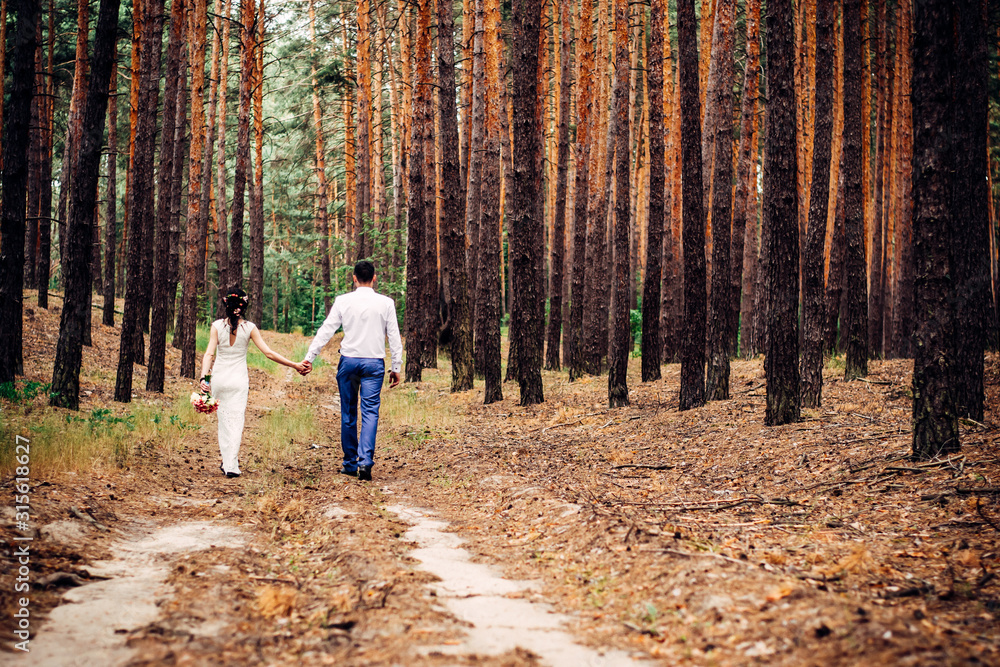 Fototapeta premium A guy with a girl walk through the forest along a country road in the mountains after rain