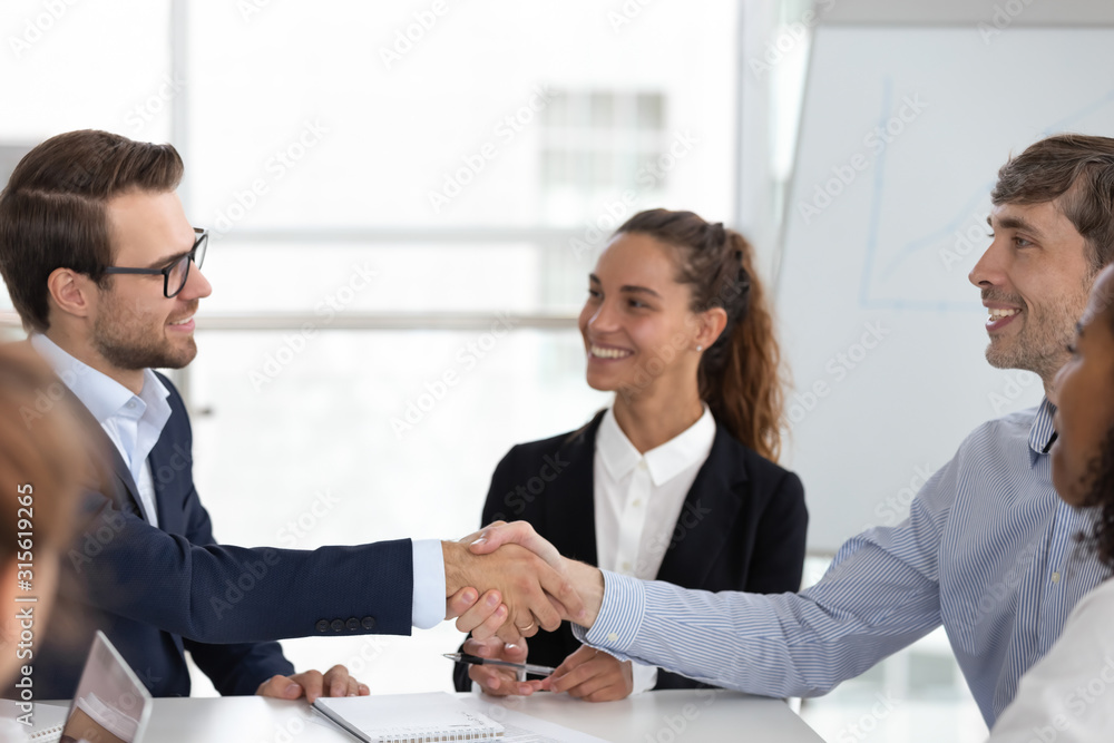 Smiling male business partners handshake at office meeting Smiling male business partners handshake at office meeting