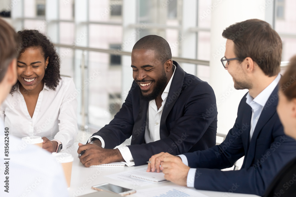 Smiling diverse employees laugh brainstorming at office meeting Smiling diverse employees laugh brainstorming at office meeting