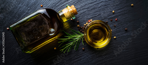 Extra virgin olive oil in a glass bottle, rosemary and peppercorns