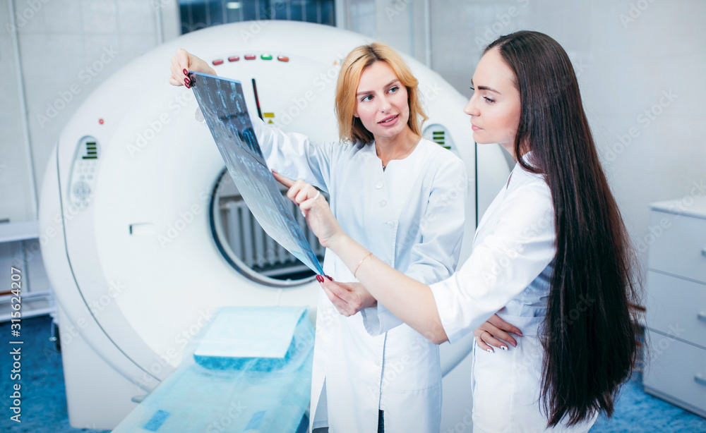 Two beautiful model girls doctors examine CT Scan picture Two beautiful model girls doctors examine CT Scan picture